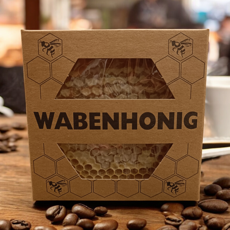 Verpackte Wabenhonig mit Bienenstock-Motiv, umgeben von Kaffeebohnen.
