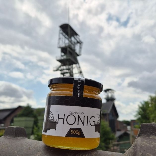 Verpackte Wabenhonig mit Bienenstock-Motiv, umgeben von Kaffeebohnen.